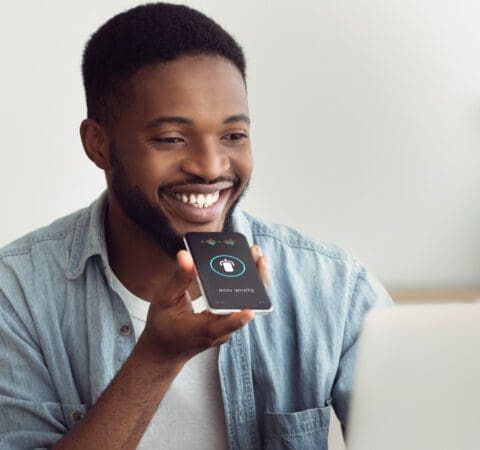 Black Guy Using Smart Phone Voice Assistant Sitting At Home