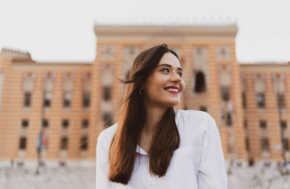 a woman smiling in front of a building